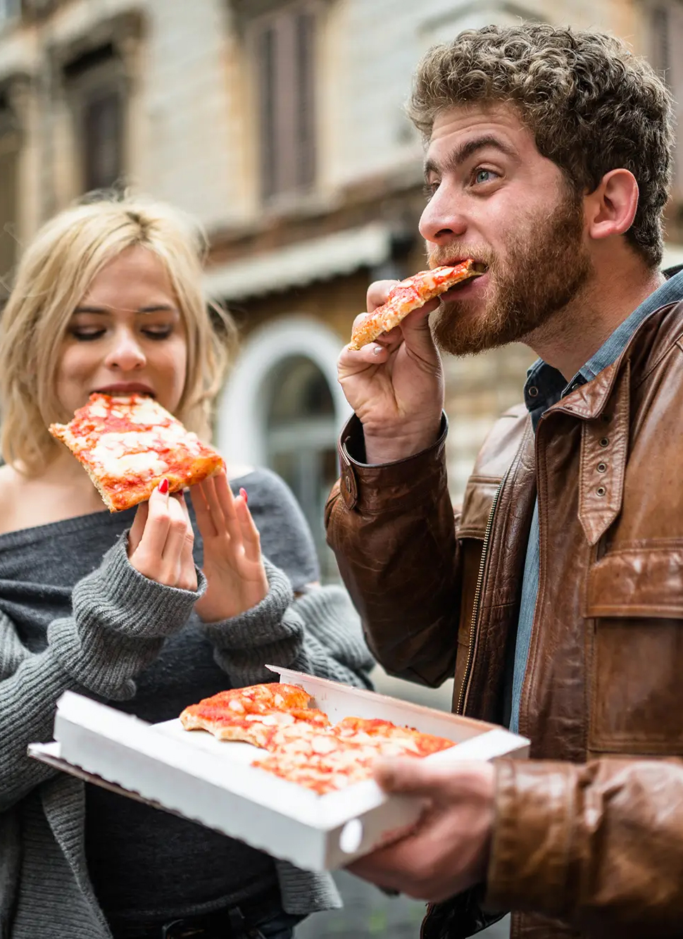 Two friends laughing and having pizza at table